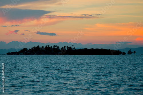 Dramatic orange tinged Sunset in the Bohol Strait. Silhoutte of Hambongan Island, a small inhabited islet off the town of Clarin. photo