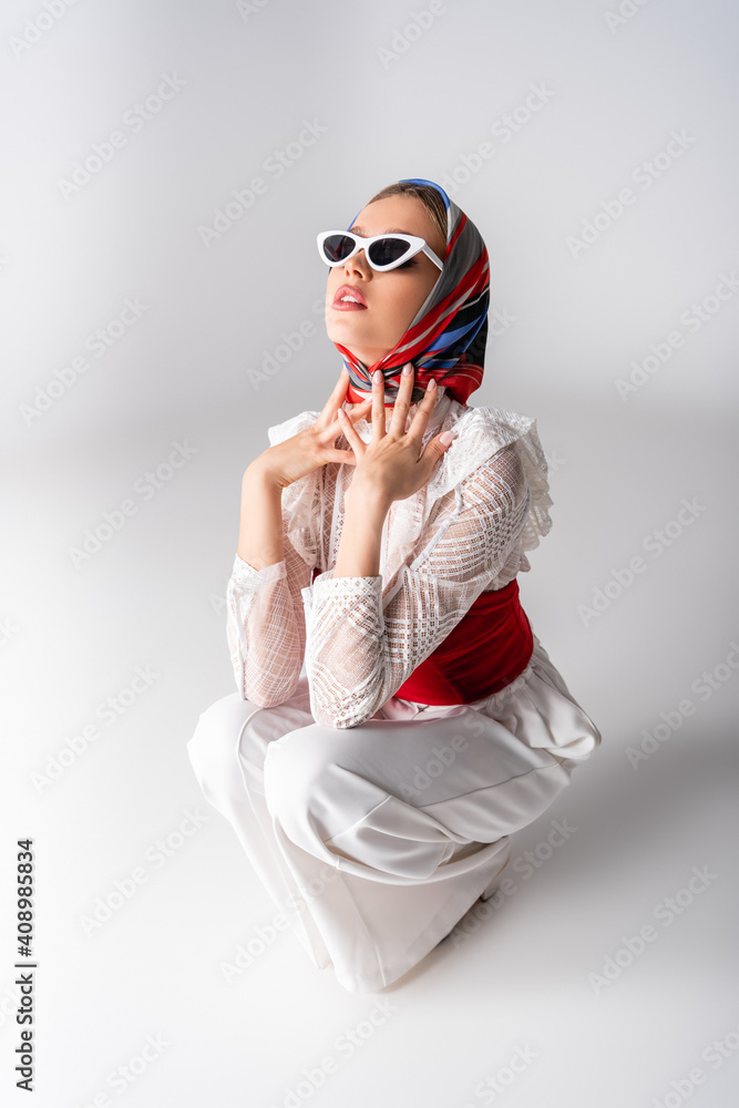 stylish woman in headscarf and sunglasses sitting on white stylish woman in headscarf and sunglasses sitting on white
