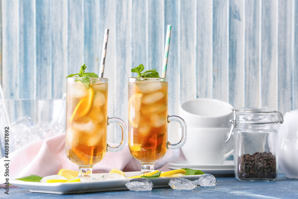 Cups of cold black tea with lemon on color background Cups of cold black tea with lemon on color background