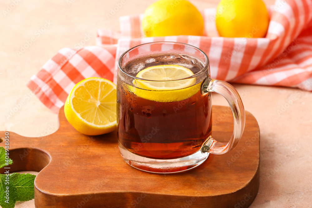 Cup of cold black tea with lemon on color background