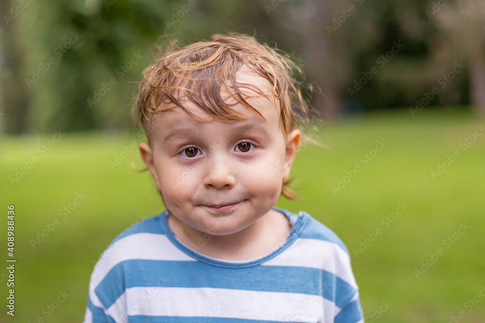 Close up portrait of a little smiling boy in the parks. Adorable child of two years old with sweaty hairs in hot summer weather. Close up portrait of a little smiling boy in the parks. Adorable child of two years old with sweaty hairs in hot summer weather.