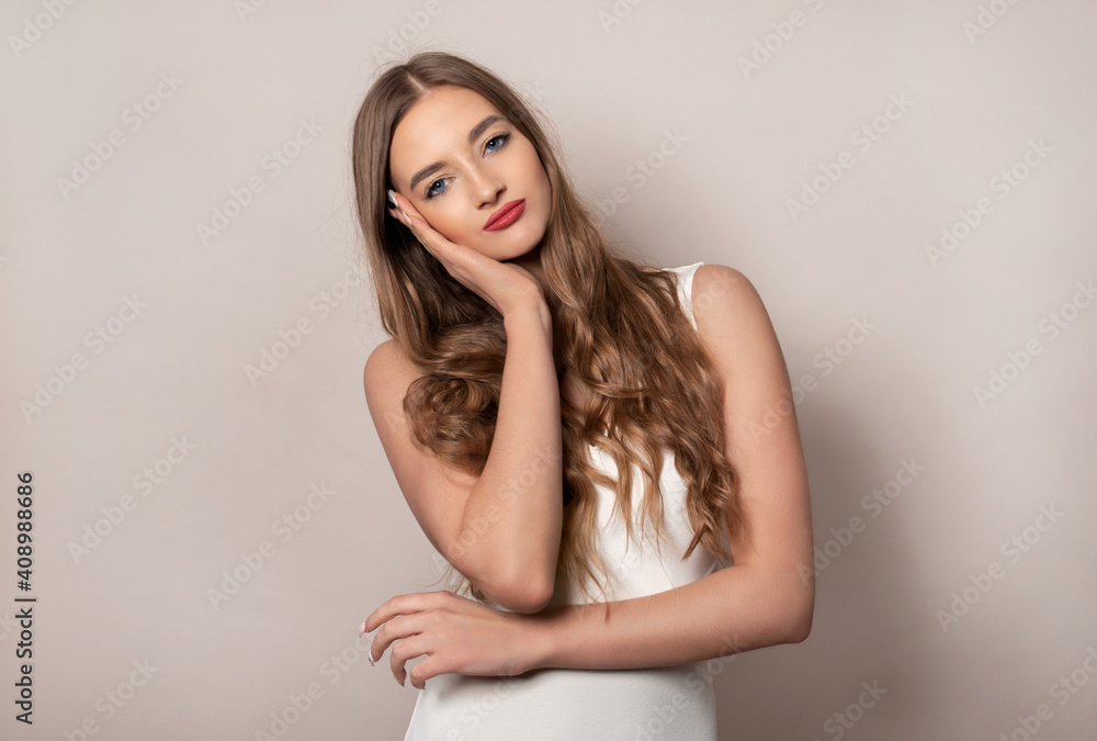 Beautiful young woman with long shiny and healthy hair posing in dress on grey background Beautiful young woman with long shiny and healthy hair posing in dress on grey background