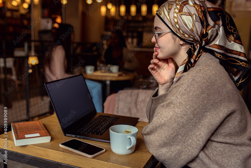 Portrait of young middle eastern woman using laptop in coffee shop. Portrait of young middle eastern woman using laptop in coffee shop.