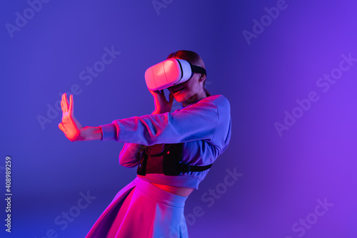 woman in virtual reality headset gesturing on purple background