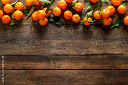 Tangerines, fresh mandarin oranges, clementines with leaves on wooden background. Top view, copy space