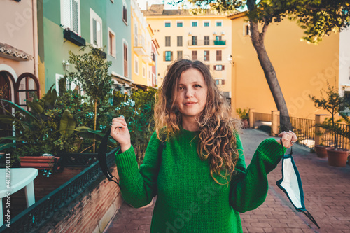 Young woman wearing green oversize sweater enjoying a windy day in a colorful city photo