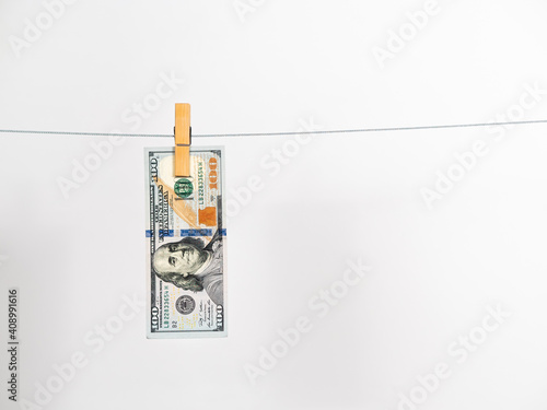 American $ 100 dollar bill hanging on a laundry string against white background. Concept of money laundering 