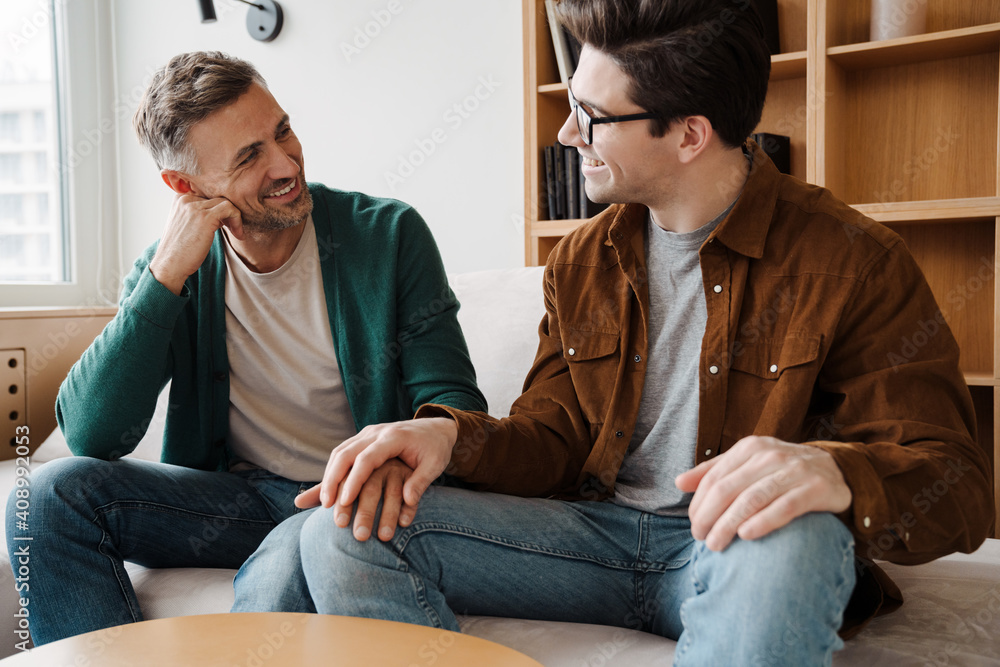Happy young male gay couple talking while relaxing Happy young male gay couple talking while relaxing