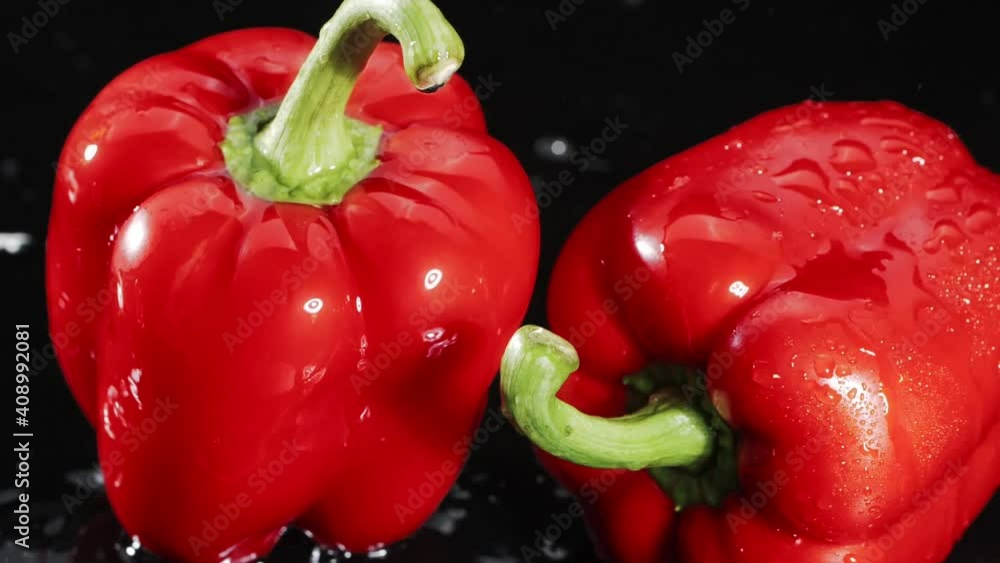 Fresh washed organic red bell pepper with water drops on a black background. Close-up of a a powerful stream of water on the surface of the vegetables. Fresh washed organic red bell pepper with water drops on a black background. Close-up of a a powerful stream of water on the surface of the vegetables.