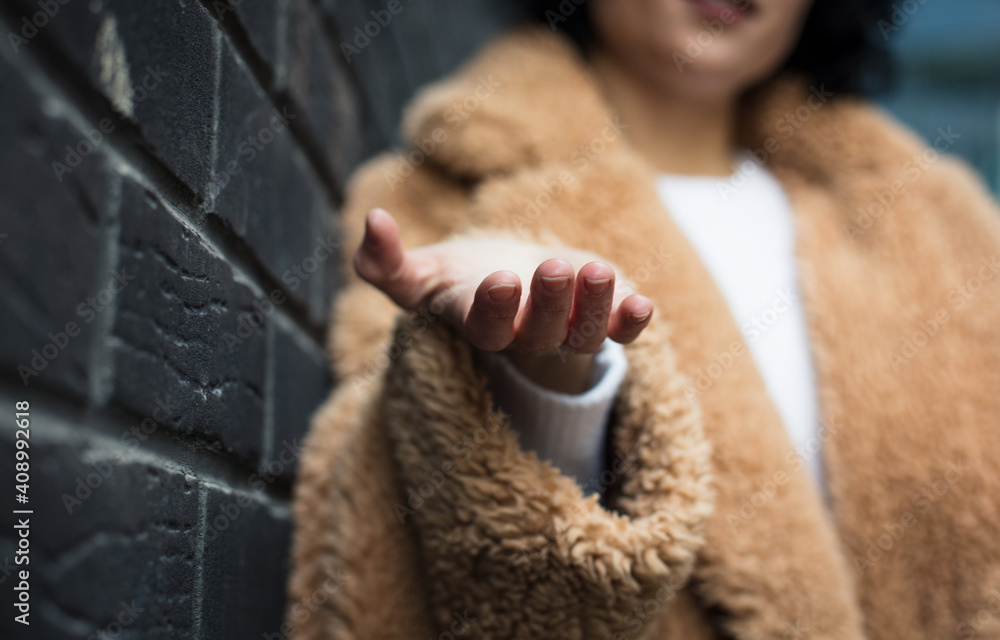 She extends her hand. Woman on street. Close up. Focus is on hand. She extends her hand. Woman on street. Close up. Focus is on hand.