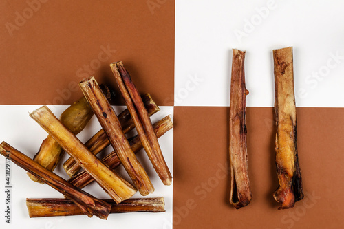 Photography Dried bovine penis, bully sticks, beef pizzle for dogs on a brown and white background