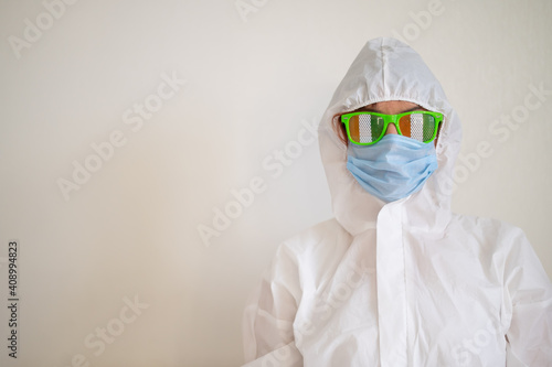 A woman in a protective suit and a medical mask and wearing funny glasses celebrates st patrick's day