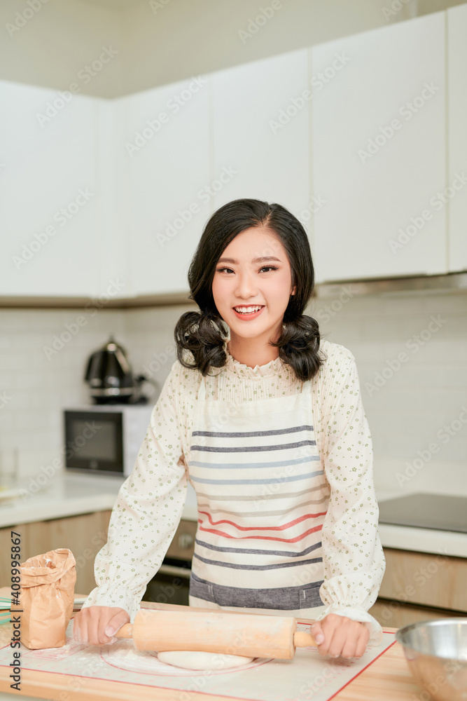 Pretty asian woman in a professional kitchen prepares the dough with flour Pretty asian woman in a professional kitchen prepares the dough with flour