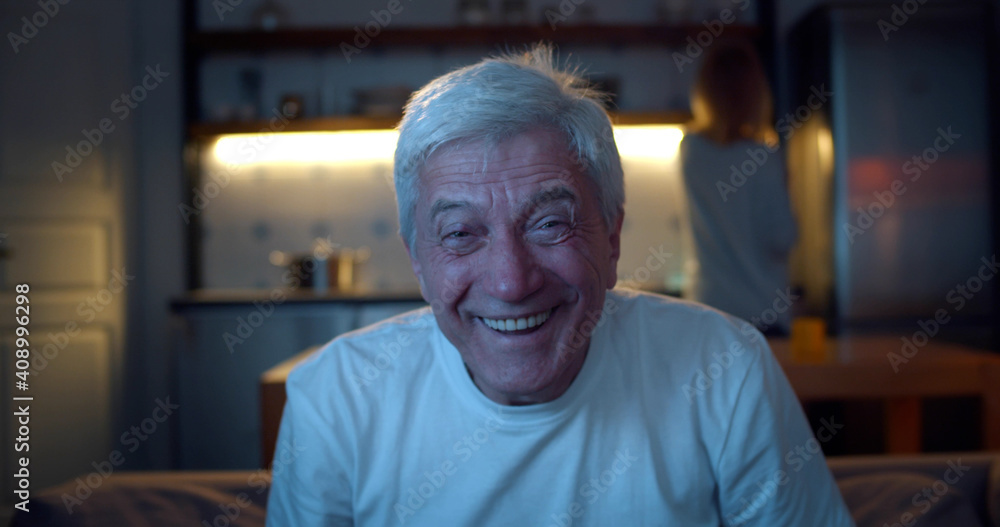Close up of aged man watching tv in evening and laughing relaxing on couch Close up of aged man watching tv in evening and laughing relaxing on couch
