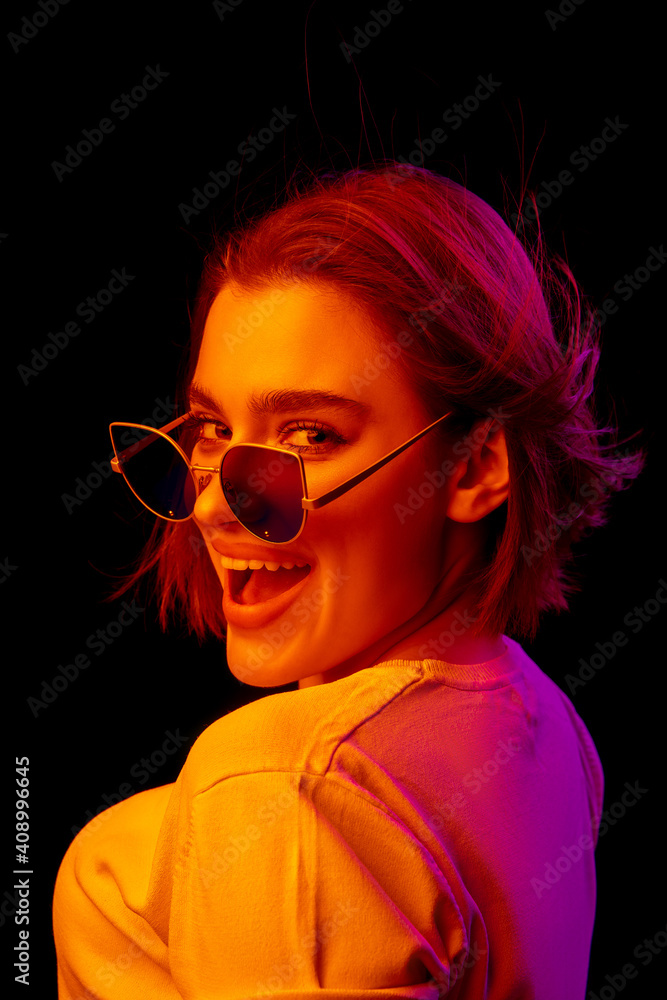 Singer. Caucasian woman's portrait on black studio background in orange-pink neon light. Beautiful female model with blowing hairs out. Concept of human emotions, facial expression, sales, ad, fashion Singer. Caucasian woman's portrait on black studio background in orange-pink neon light. Beautiful female model with blowing hairs out. Concept of human emotions, facial expression, sales, ad, fashion