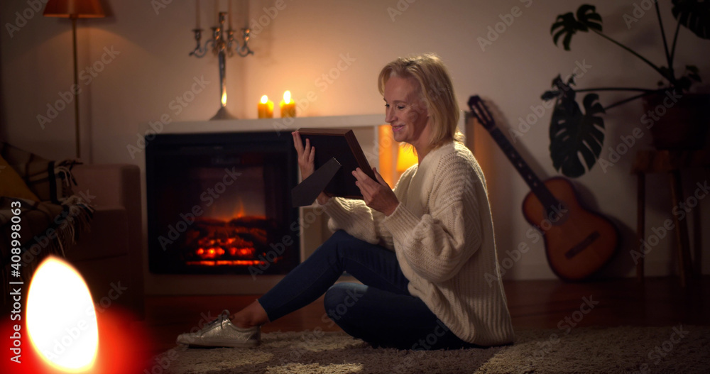 Happy mature woman looking at photograph in frame at home