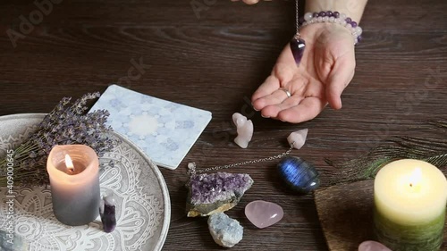 Close up of  hand holding and using amethyst crystal pendulum on silver chain. Fortune telling concept. photo