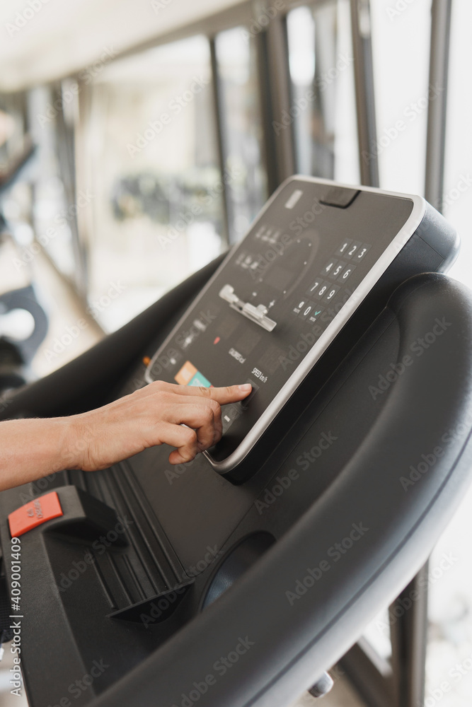 Naklejka premium Woman changing settings on a treadmill in a gym
