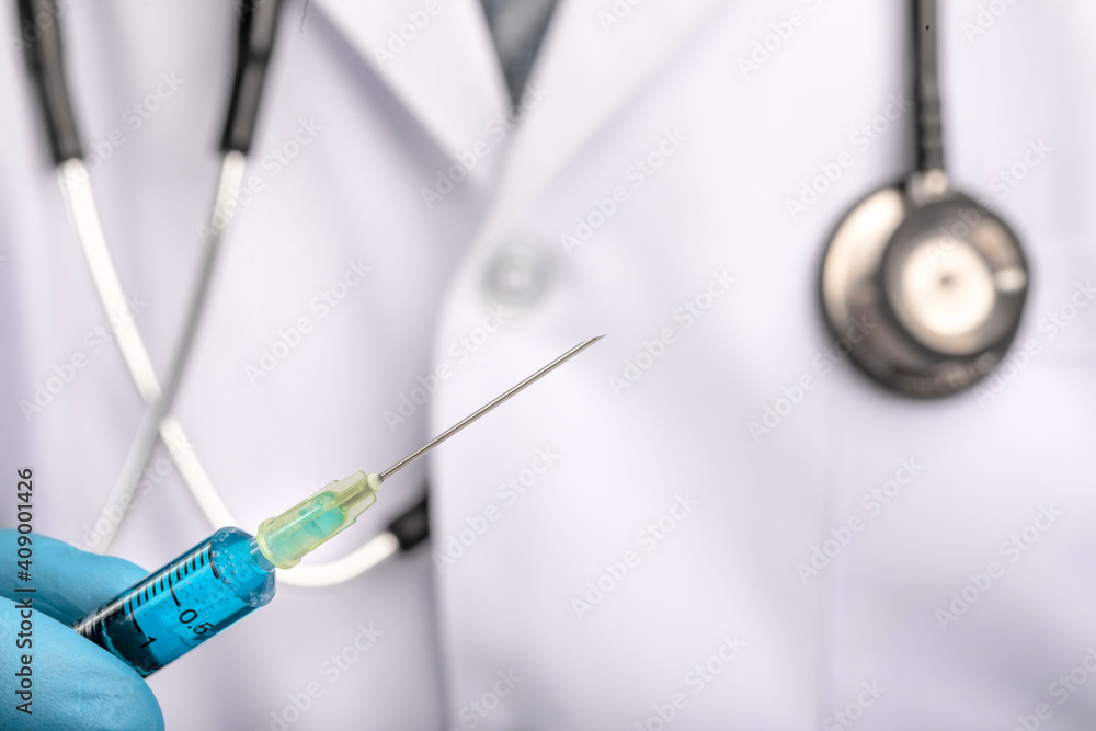 Fighting covid-19 corona virus image, a doctor or a scientist in a laboratory coat holding a syringe with liquid vaccine. Concept: diseases, medical care, science.. Fighting covid-19 corona virus image, a doctor or a scientist in a laboratory coat holding a syringe with liquid vaccine. Concept: diseases, medical care, science..