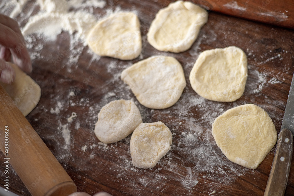 Senior woman hands rolling out dough in flour with rolling pin in her home kitchen Senior woman hands rolling out dough in flour with rolling pin in her home kitchen