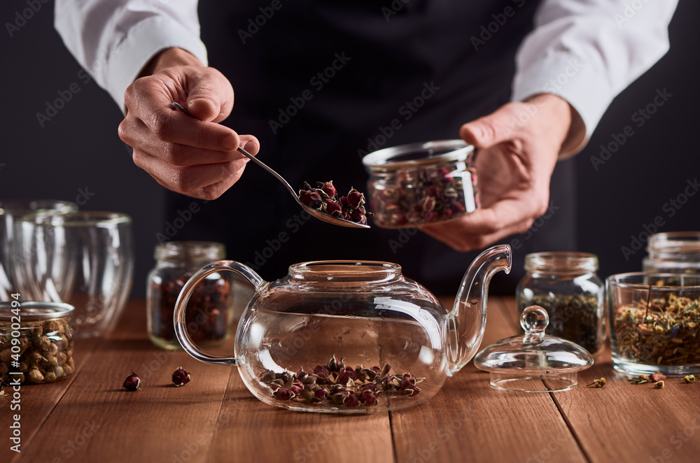 Tea master putting rose buds into a glass teapot Tea master putting rose buds into a glass teapot