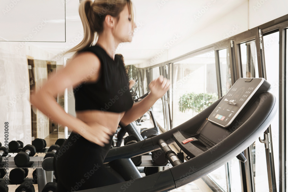 Athletic woman running on treadmill during fitness workout - obrazy, fototapety, plakaty 