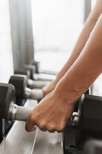 Female hands and dumbbells on the rack in gym