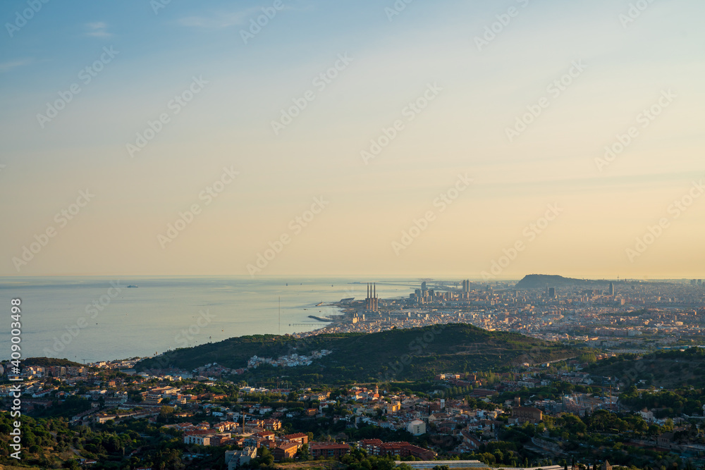 Obraz premium Panoramic view of the entire city of Barcelona and its surroundings. During sunset one day in late summer. We can see the Mediterranean sea completely flat.