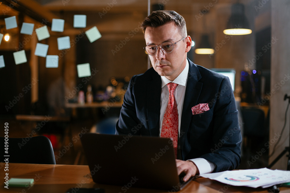 Young businessman using laptop in his office. Handsome man working at his workplace
