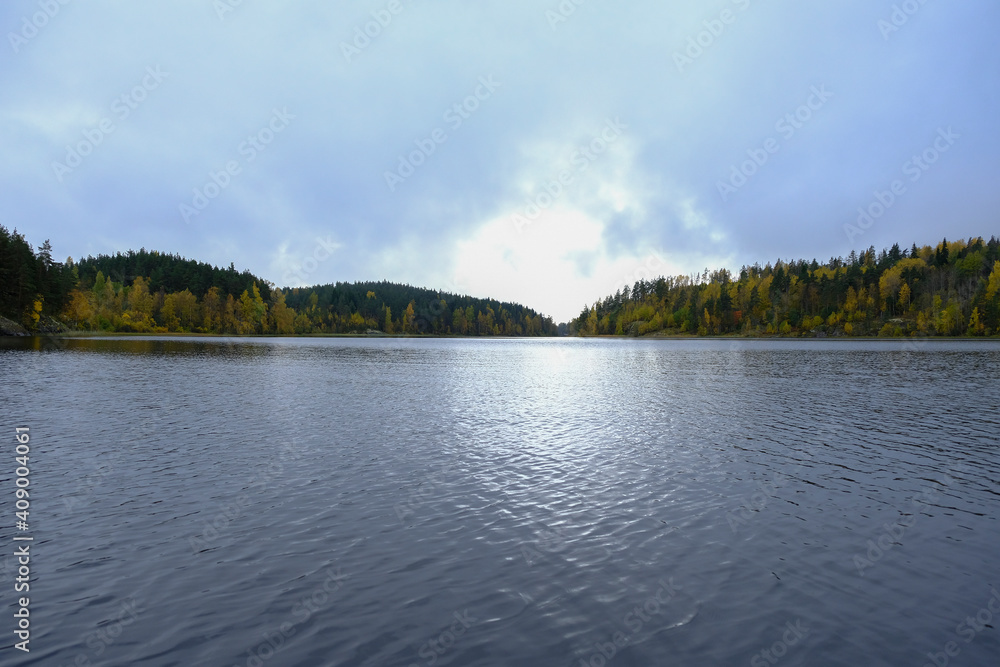 Beautiful Ladoga lake with forest on bank and clouds reflections on water, Karelia.Autumn season landscape background. Adventure tourism. Travel in Russia concept. Beautiful places in Russia.