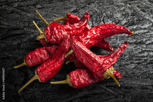 Red dried chili peppers. Top view of a pile of hot dry peppers on a black charcoal surface.