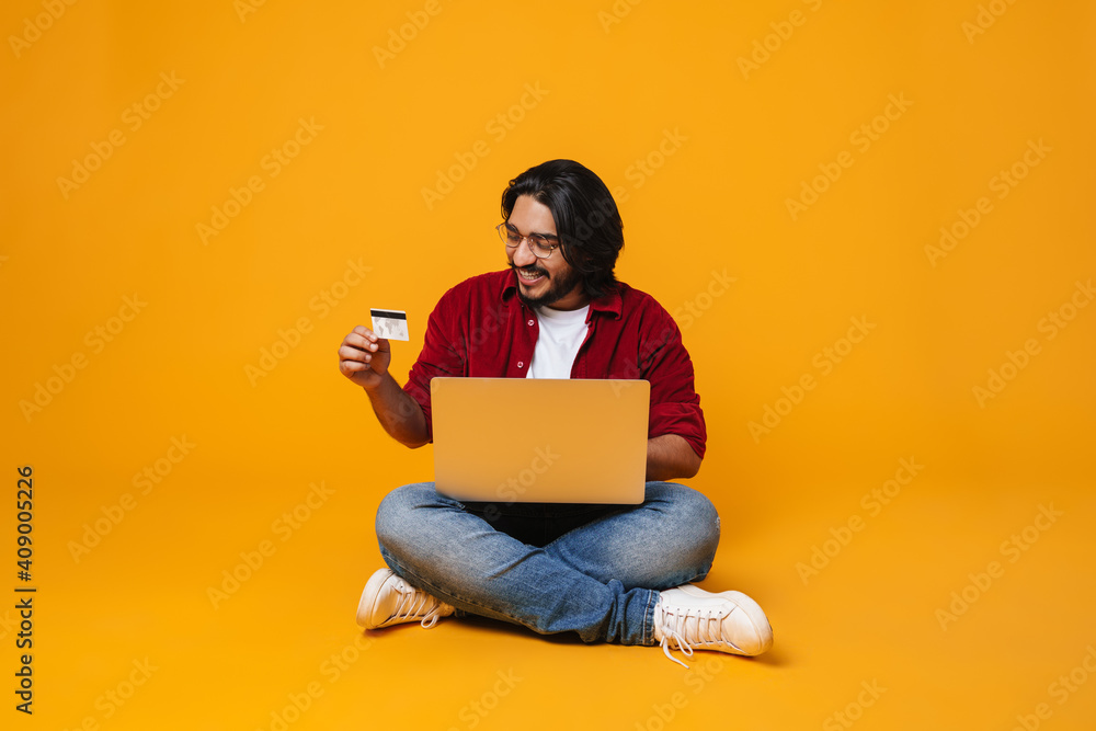 Happy indian man using laptop for shopping online