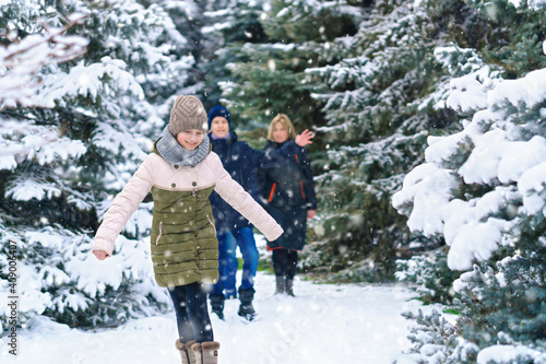 family walking in the winter forest, two parents and two children, beautiful nature with bright snowy fir trees © soleg