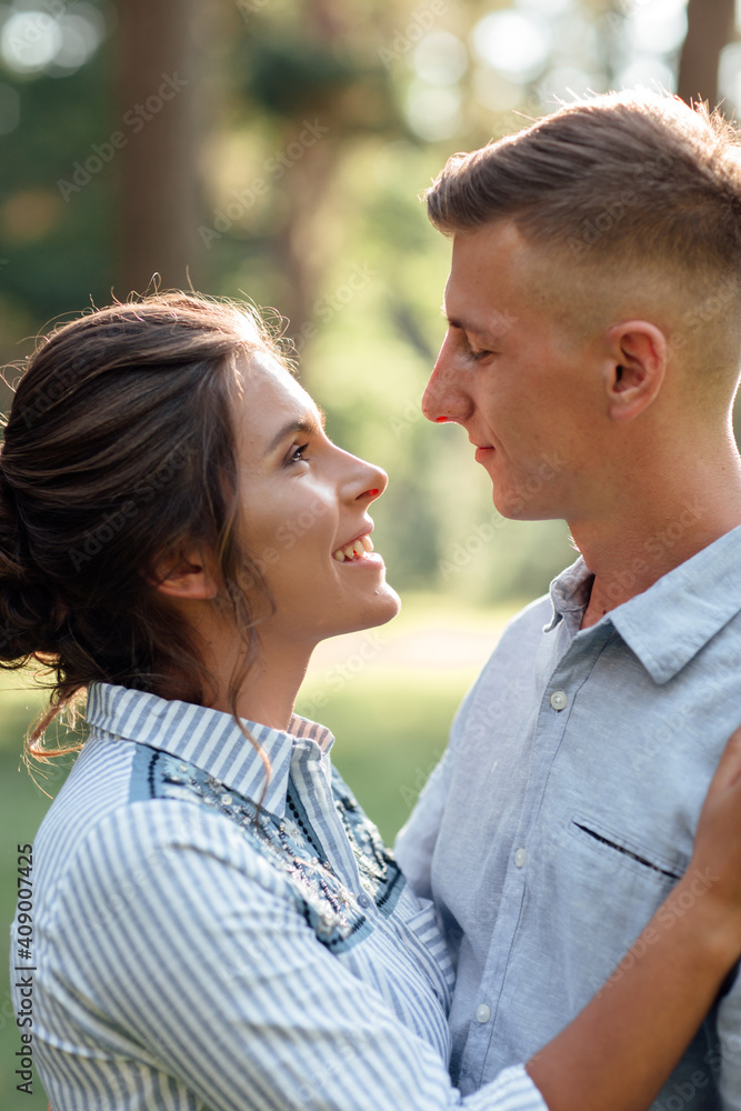 Cheerful young woman and man are hugging outdoors in summer park. Dating and romantic vacation. couple in love gently looking at each other on sunny day. Love and relationships between young people Cheerful young woman and man are hugging outdoors in summer park. Dating and romantic vacation. couple in love gently looking at each other on sunny day. Love and relationships between young people