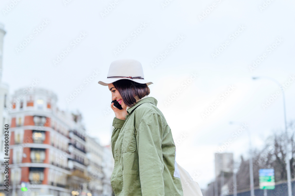 young woman crossing the street while holding smartphone