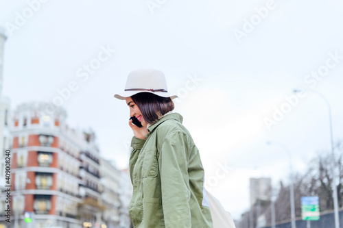 young woman crossing the street while holding smartphone © Miguel Lifestyle