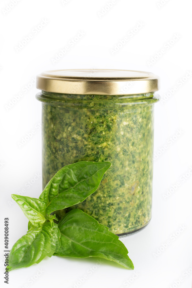 Pesto sauce in a glass jar isolated with fresh basil leaves on white background. Traditional homemade Italian sauce pesto and basil leaves Pesto sauce in a glass jar isolated with fresh basil leaves on white background. Traditional homemade Italian sauce pesto and basil leaves