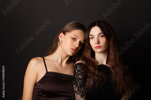 two beautiful young women with makeup and hairstyle on a black background 