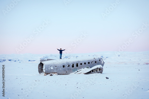 Man cheerfully standing on a plane wreck in Solheimasandur, Iceland