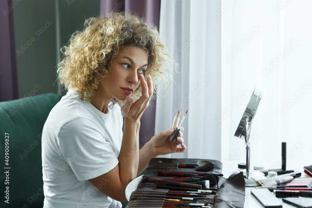 Beautiful woman is applying concealer under her eyes Beautiful woman is applying concealer under her eyes
