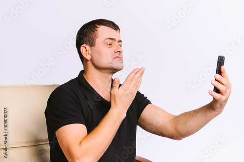 Senior man in a chair shows with gestures a sign, please, communicating via video communication. White background and empty side space.