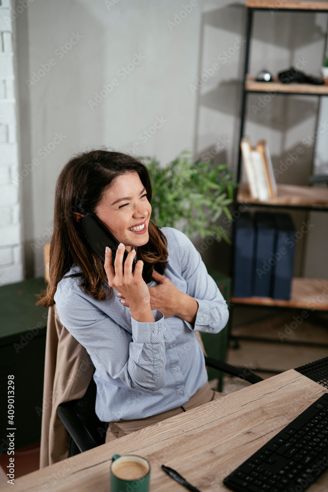 Businesswoman using the phone in office. Beautiful young woman working on computer at her workplace.. Businesswoman using the phone in office. Beautiful young woman working on computer at her workplace..