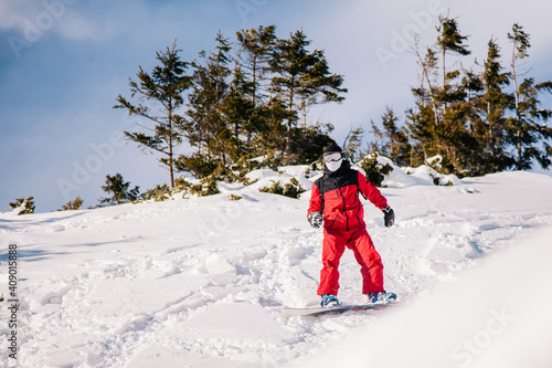 A guy in a red jumpsuit eating freeride on a snowboard on a snowy slope