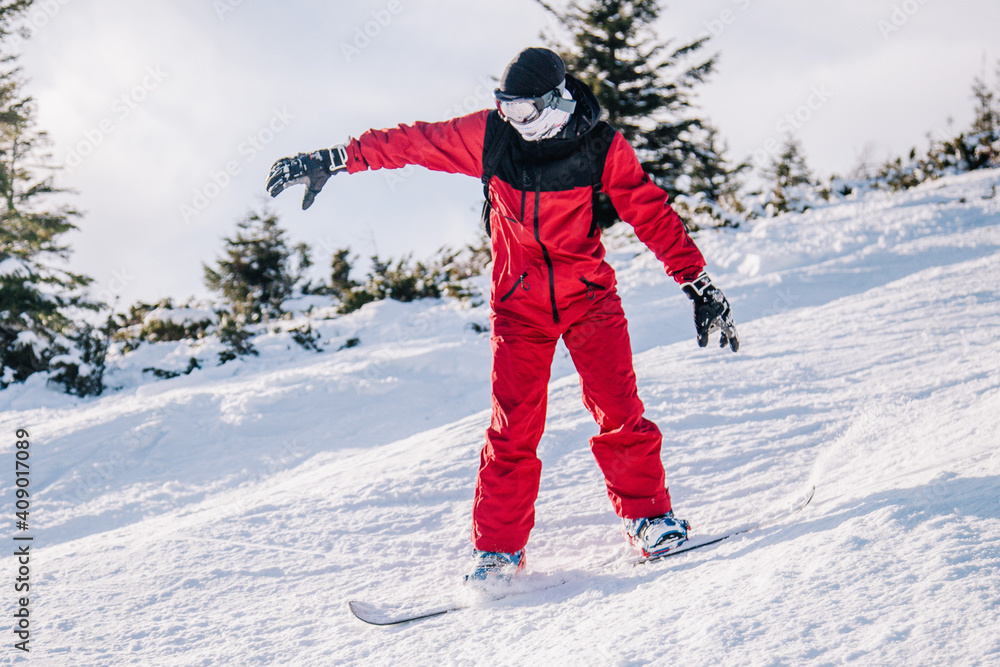 A guy in a red jumpsuit eating freeride on a snowboard on a snowy slope A guy in a red jumpsuit eating freeride on a snowboard on a snowy slope