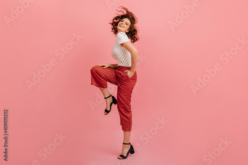 Full length view of joyful woman standing on one leg. Studio shot of wonderful short-haired girl dancing on pink background.