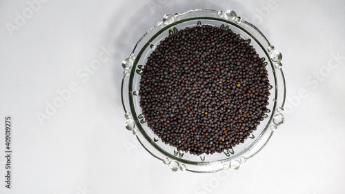 mustard seeds in glass bowl on a white isolated surface