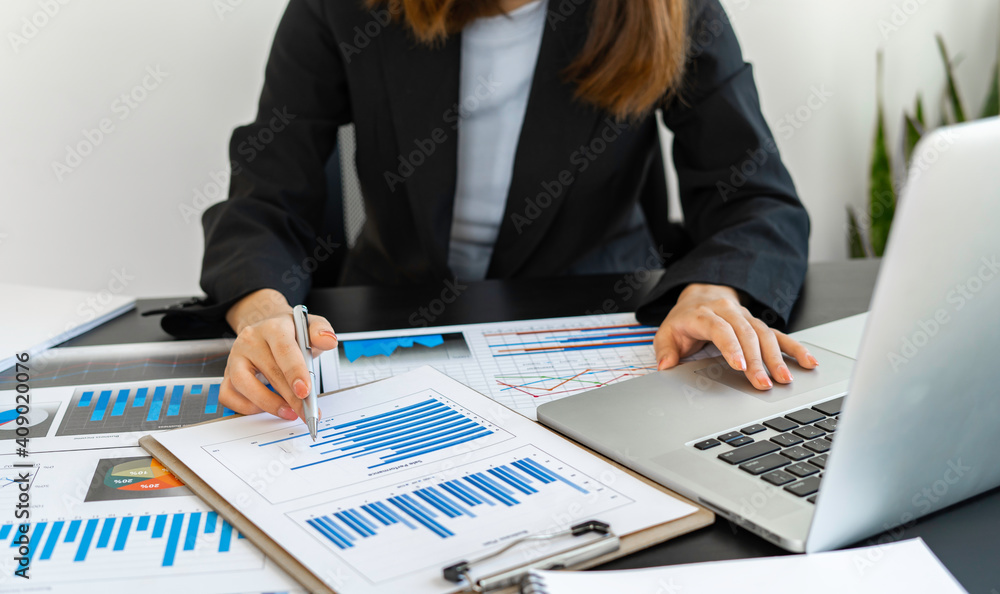 The hand of the money manager takes notes and uses the laptop When working on reports About the results of investment in the company The hand of the money manager takes notes and uses the laptop When working on reports About the results of investment in the company