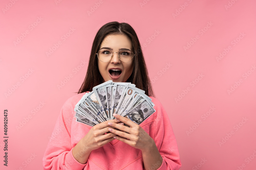 Photo of attractive woman in glasses surprised and happy for salary, wears casual pink t-shirt white pants isolated pink color background Photo of attractive woman in glasses surprised and happy for salary, wears casual pink t-shirt white pants isolated pink color background