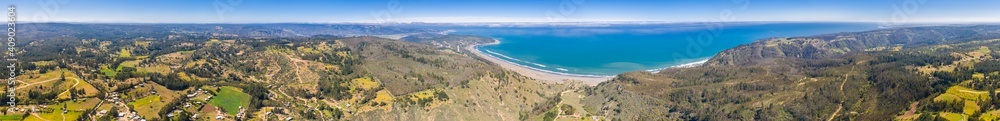 Amazing aerial view of central Chilean coastline with at Puertecillo. A rugged landscape from the ground down to the cliffs and the amazing and wild sea. Awe sunny day with clouds in the far horizon