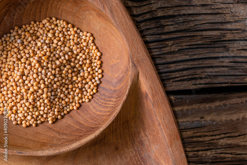 Close up of mustard seeds/Rai or brown mustard seeds in a small plate on a wooden background